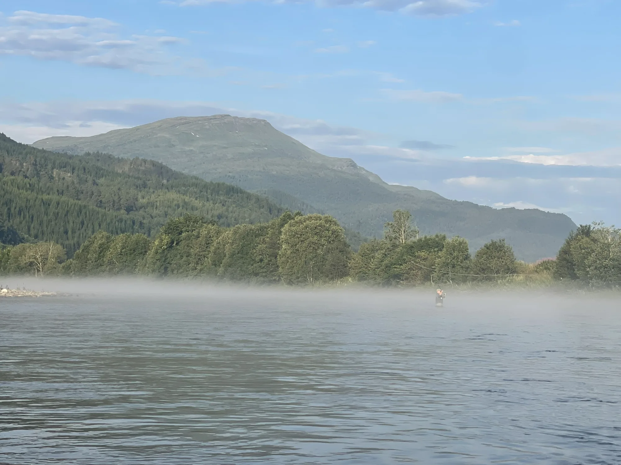 Angler in the morning mist on still water